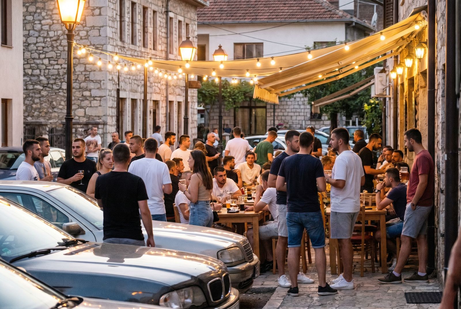 Të rinj ulur në një tarracë kafeje plot gjallëri një mbrëmje vere në një qytet të Kosovës