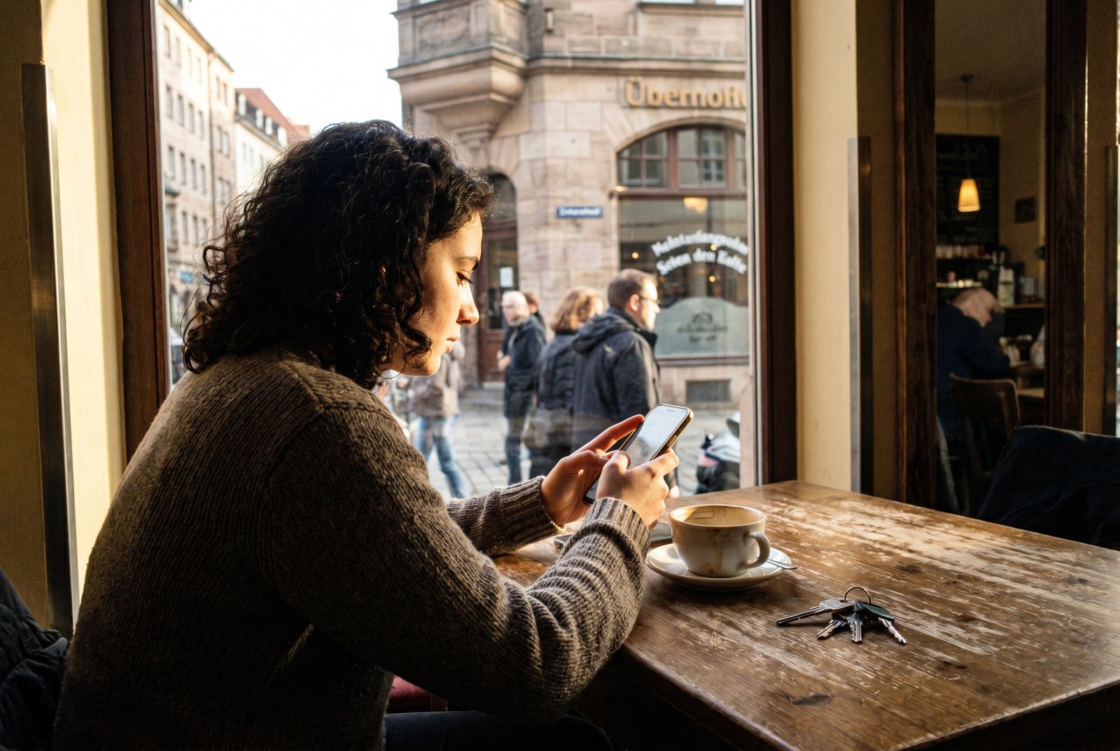 Person i ri ulur në një kafene duke shkruar një mesazh në telefon